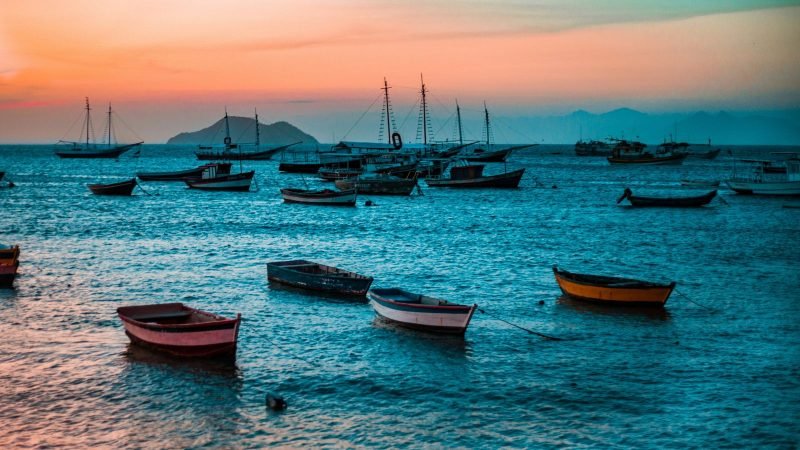 Pôr do sol com barcos de pesca na orla de Búzios