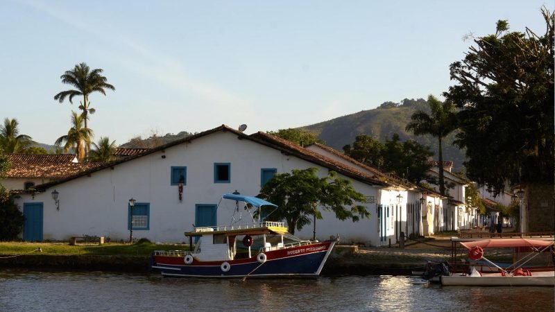 Orla de Paraty com casario colonial e barco típico à beira do rio